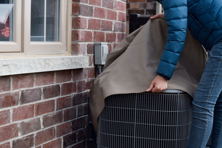 man covering HVAC outside home